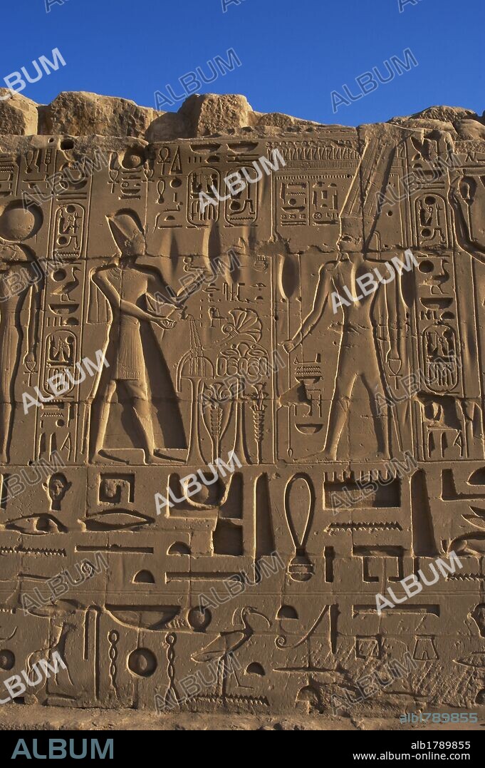 ARTE EGIPCIO. EGIPTO. Relieve con la representación del faraón RAMSES II, con yelmo o corona "Khepresh", portando un incensario para realizar la ofrenda de "La fragancia divina" al diós AMON, representado con dos largas plumas segmentadas. XIX Dinastía. Imperio Nuevo. Templo de Karnak. Noroeste de Luxor. Egipto.