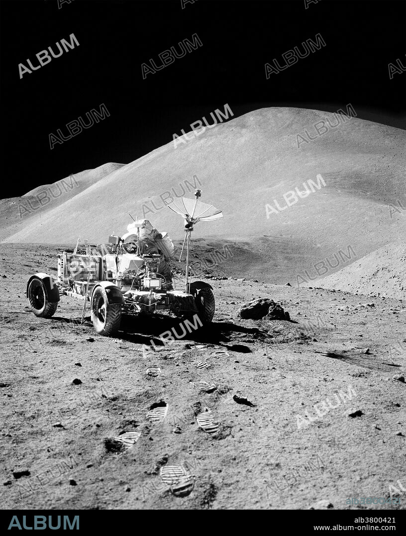 Astronaut David R. Scott, commander of Apollo 15, works at the Lunar Roving Vehicle (LRV) during the third lunar surface extravehicular activity (EVA) of the mission at the Hadley-Apennine landing site on August 2, 1971. Hadley Rille is at the right center of the picture. Hadley Delta (background) rises approximately 4,000 meters (about 13,124 feet) above the plain. St. George Crater is partially visible at the upper right edge. This photograph was taken by astronaut James B. Irwin, lunar module pilot, looking almost due south.