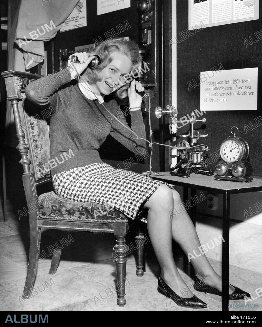 Stockholm 1964-03-03. Fru Kersti Sone provar en telefonapparat från 1884 med två hörlurar på utställningen "Telefonparaden - från Bell till våra dagar". Foto: Herman Ronninger / SvD / TT / kod 12014.