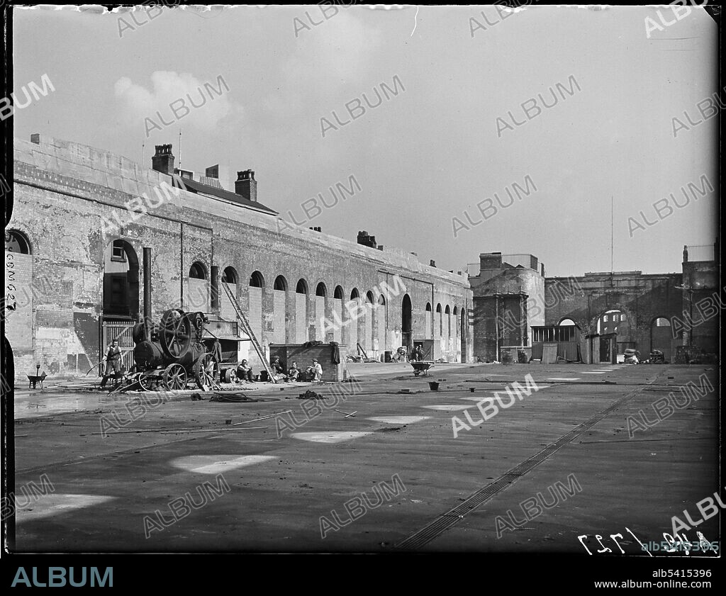 GEORGE BERNARD MASON. Market Hall, Worcester Street, Bull Ring, Birmingham, 1941. Construction workers beside a traction engine inside the bombed out shell of the Market Hall. The former Market Hall dated from the 1830s. It was destroyed during the Birmingham Blitz and remained as an empty shell until it was demolished in 1963 as part of the Bull Ring Centre development. This view shows the windows bricked up and the roof missing as a result of the incendiary devices dropped on the 25th August 1940.