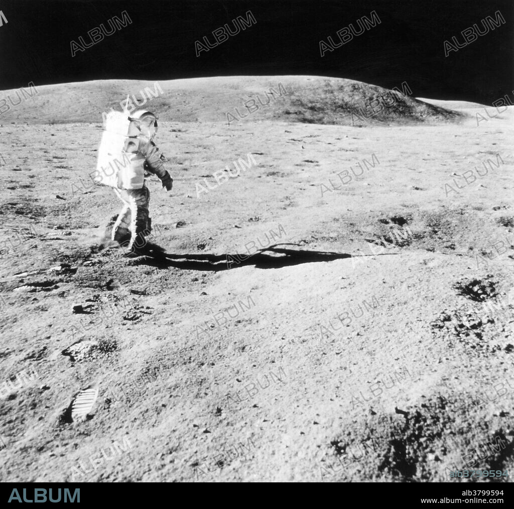 Astronaut Charles M. Duke, Jr., Apollo 16 lunar module pilot, walks at the first geological stop (near Plum Crater) during the first extravehicular activity (EVA-1), April 21, 1972. Stone Mountain is visible in the background. This image was captured by Astronaut John W. Young, commander.