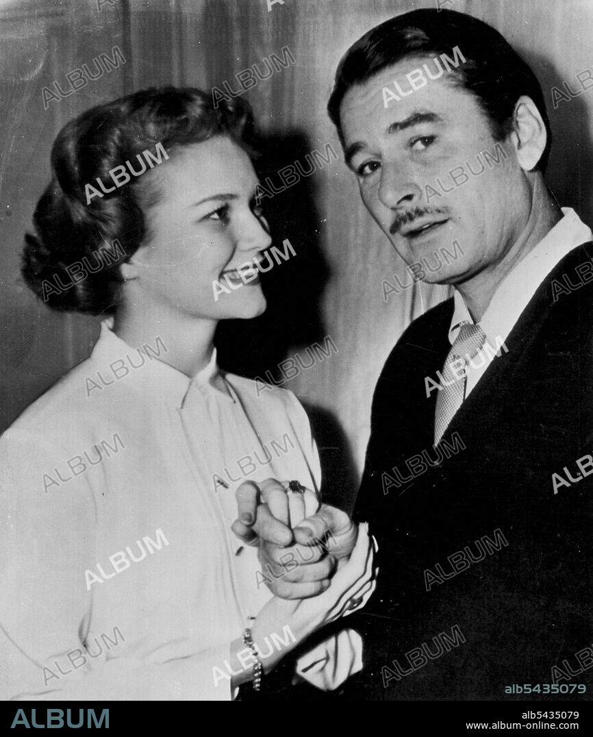 Look at Her Third Finger, Left Hand -- Screen actress Patrice Wymore, wearing the six carat sapphire ring given her by her fiance, actor Errol Flynn, gives him an endearing smile as they post in a Paris hotel Thursday. The sapphire of deep blue--matching the color of Miss Wymore's eyes--was crusted with baguette diamonds. No one would say how it cost. The couple will be married in both civil and Protestant ceremonies in Monte Carlo Oct. 23. September 30, 1950. (Photo by AP Wirephoto).