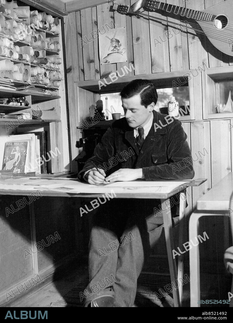 Drevviken 1944-12-24. Lådan, arkitekten Ralph Erskines första egenritade hem i Drevviken. Ralph sitter vid sitt arbetsbord som efter användning kan fällas in i väggen.. Foto: SvD / TT / kod 12014.