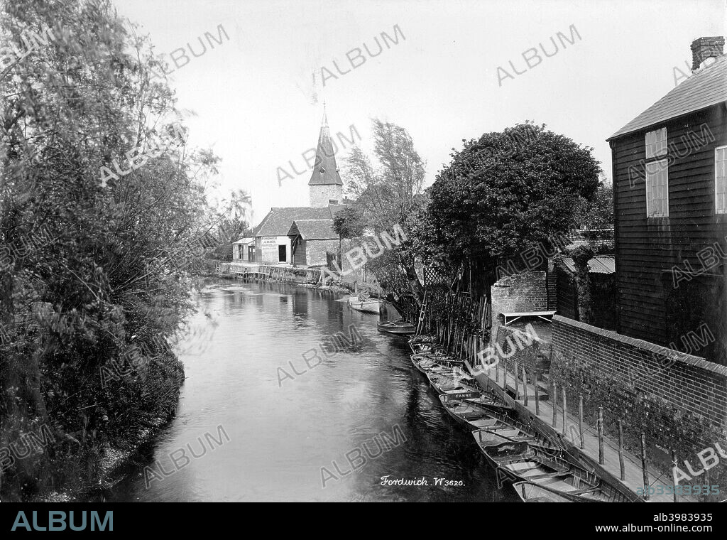 Fordwich, Kent, 1890-1910. A view along the river looking towards the Fordwich Arms and the tower of St Mary's Church which retains some of its Saxon work. A number of rowing boats are moored by the bank of the river, possibly intended for the tourist trade.