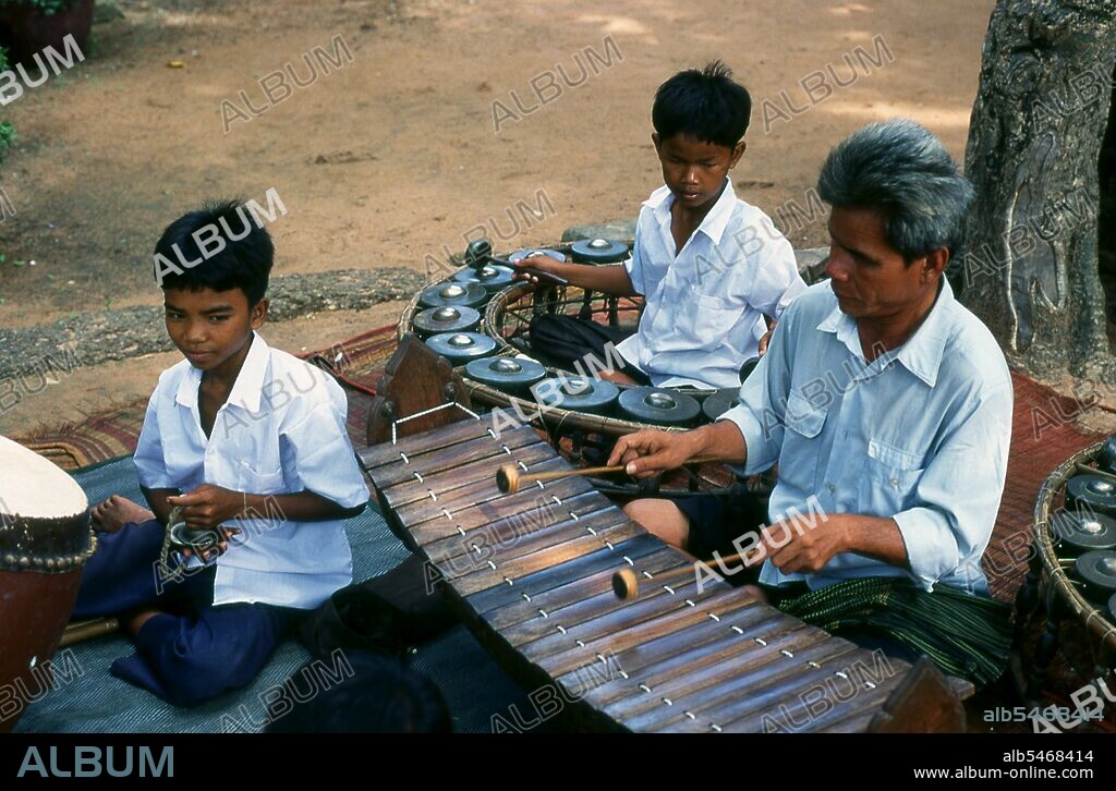 The pinpeat orchestra or musical ensemble performs the ceremonial music of the? royal courts and temples of Cambodia. The orchestra consists of approximately nine or ten instruments, mainly wind and percussion (including several varieties of xylophone and drums). It accompanies court dances, masked plays, shadow plays, and religious ceremonies. The pinpeat is analogous to the piphat ensemble of Thailand. Seen here are a roneat thung or low-pitched xylophone and a kong thom or gong circle. The laterite temple of Ta Prohm was built by King Jayavarman VII on top of an earlier 6th century Khmer shrine. The result is a well-preserved gem of a temple, not unduly large, but with some splendid decorative features. The main sanctuary has five chambers, in each of which is a statue or a Shiva lingam.