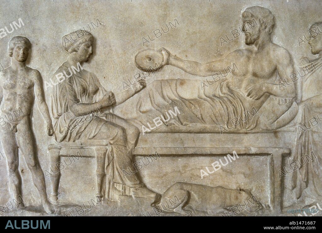 PERIODO CLASICO. GRECIA. RELIEVE CON ESCENA DE UN BANQUETE FUNERARIO. El hombre acostado sostiene en su mano un "philae" y un muchacho sirve vino de una crátera. El hombre de pie representa a un adorante. Fechado en el 400 a. C., fue hallado en el Asklepieion (El Pireo). Museo Arqueológico Nacional. Atenas.