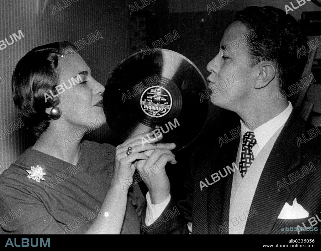 Young Australian Singer Gets Recording Contract -- Jim Parkinson and his wife Faye give a kiss to his first record.24-year-old Jim Parkinson, from Sydney, Australia, who arrived in this country with his charming newly wed wife Faye aged 23 only October last, has landed a contract with Columbia, for whom he will sing exclusively, his first record "All At Once" is being released on Saturday next. In his native Australia he has over 1,000 broadcasts to his credit and some 60 recordings. Since arriving here he has appeared with Ted Heath and Cyril Stapleton. Jack Hylton wants to present him in "Youth Takes a Bow" at the end of November. November 18, 1955. (Photo by Scotnews).