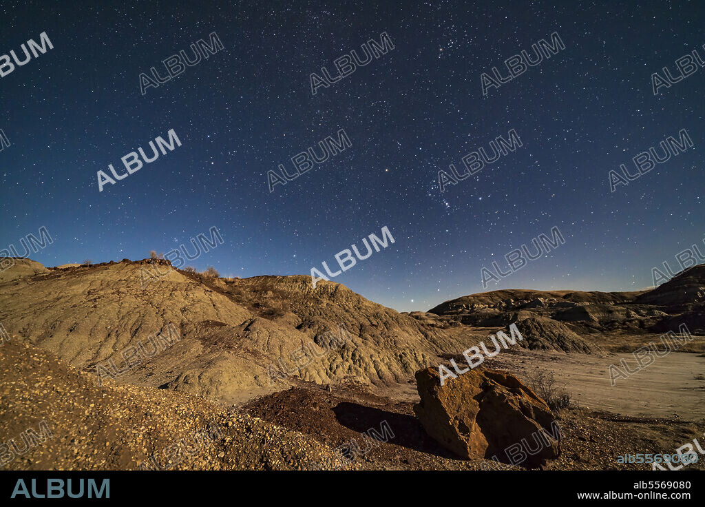 November 27, 2017 - Orion and the winter stars and constellations rising over the moonlit badlands of Dinosaur Provincial Park, Alberta, Canada. Orion is at centre; Taurus above, and Gemini at left. Sirius is just rising above the hill in the distance at centre. Serves as a good illustration of the Belt of Orion pointing up to Taurus and down to Sirius.