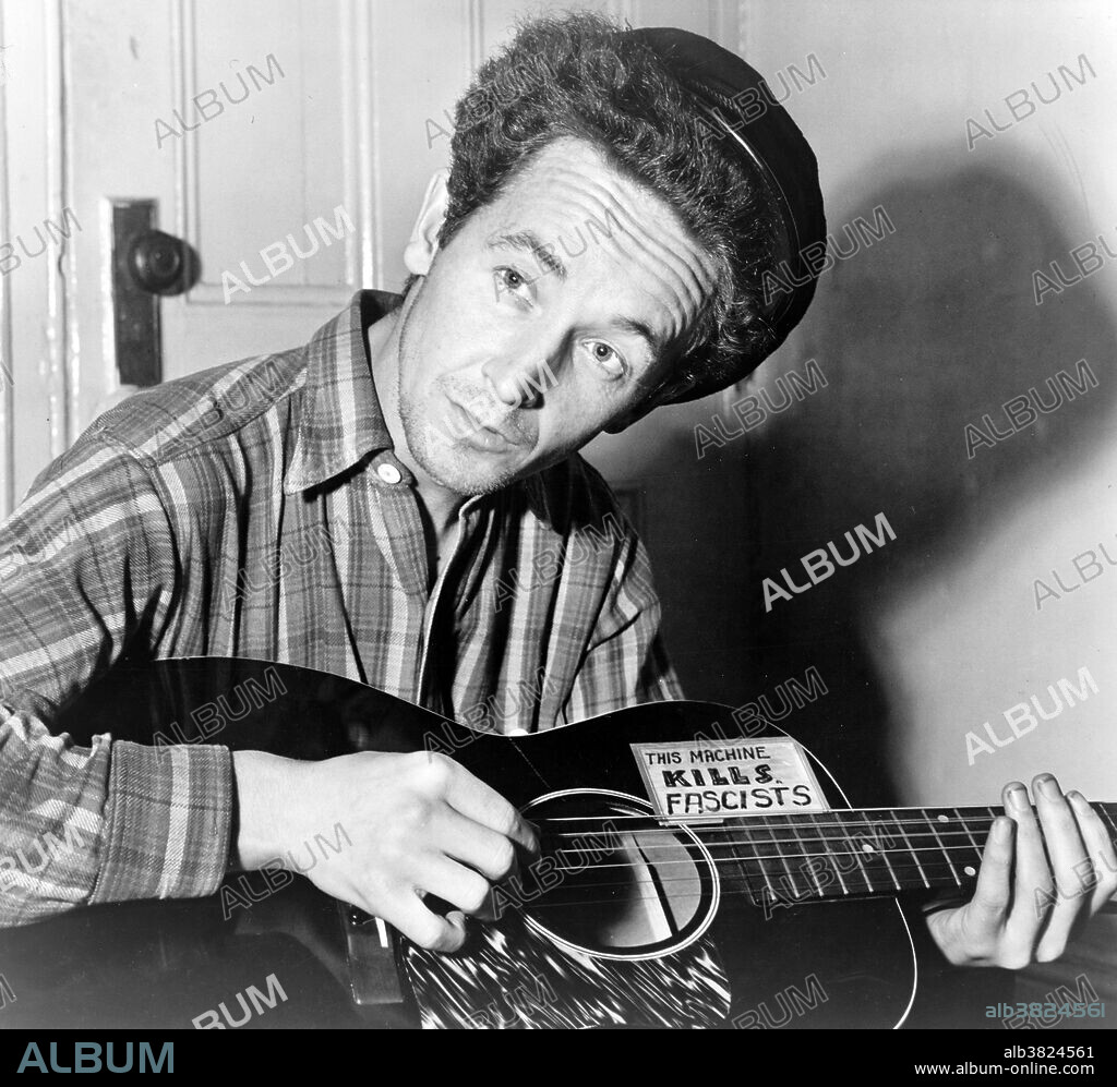 Woodrow Wilson "Woody" Guthrie (July 14, 1912 - October 3, 1967) was an American singer-songwriter and musician whose musical legacy includes hundreds of political, traditional and children's songs, ballads and improvised works. He frequently performed with the slogan This machine kills fascists displayed on his guitar. His best-known song is "This Land Is Your Land." Many of his songs are about his experiences in the Dust Bowl era during the Great Depression when Guthrie traveled with displaced farmers from Oklahoma to California and learned their traditional folk and blues songs, earning him the nickname the "Dust Bowl Troubadour." Throughout his life Guthrie was associated with United States Communist groups, though he was seemingly not a member of any. Guthrie was married three times and fathered eight children, including American folk musician Arlo Guthrie. He died in 1967, at the age of 55, from complications of Huntington's disease, a progressive genetic neurological disorder. During his later years, in spite of his illness, Guthrie served as a figurehead in the folk movement, providing inspiration to a generation of new folk musicians. Photographed by Al Aumuller for New York World Telegram & Sun, dated March 8, 1943.