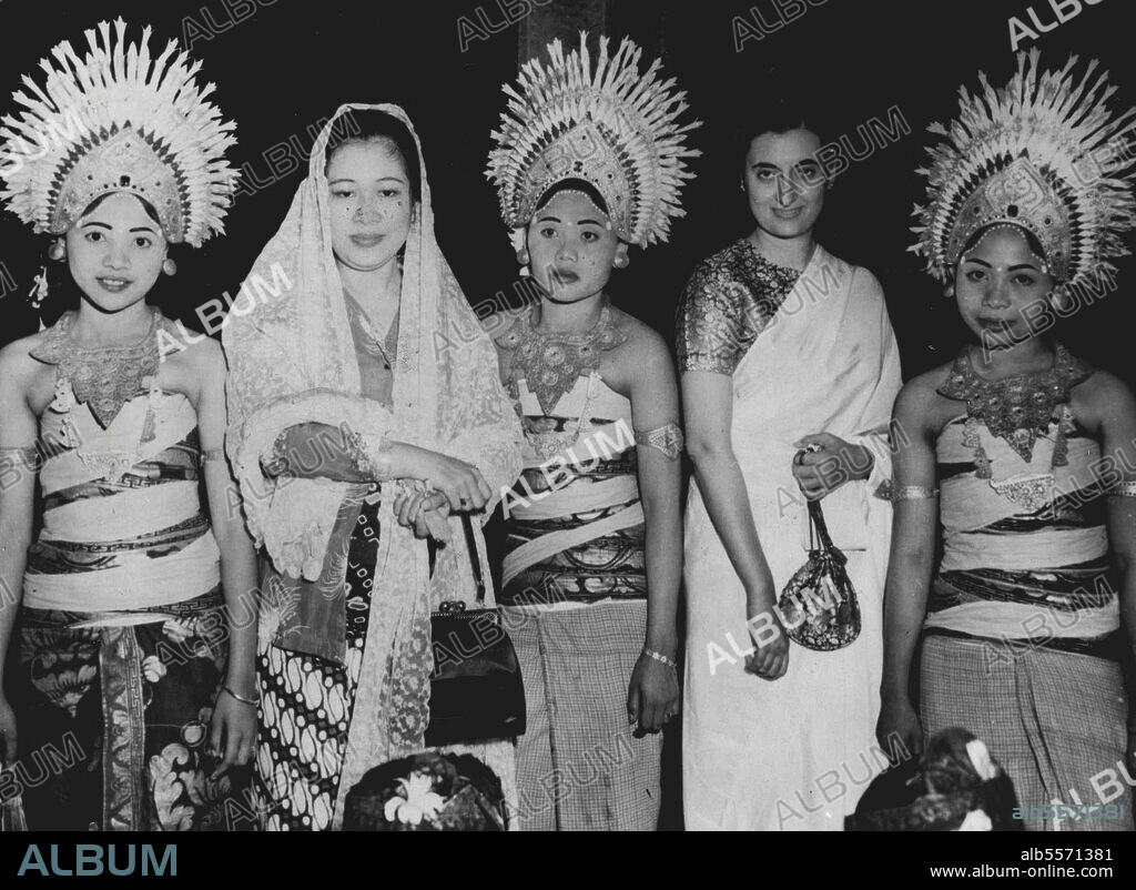 Dancing girls of the Island of Bali wear flower-topped headdresses of gold as they frame the wife of President Soekarno of Indonesia (left) and Mrs. Indira Gandhi, daughter of Premier Jawaharlal Nehru of India (right), during the state visit made to Indonesia by Nehru in mid-June. June 22, 1950. (Photo by Associated Press Photo).