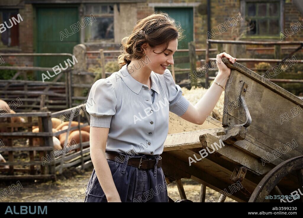 LILY JAMES en LA SOCIEDAD LITERARIA Y EL PASTEL DE PIEL DE PATATA, 2018 (THE GUERNSEY LITERARY AND POTATO PEEL PIE SOCIETY), dirigida por MIKE NEWELL. Copyright BLUEPRINT PICTURES.