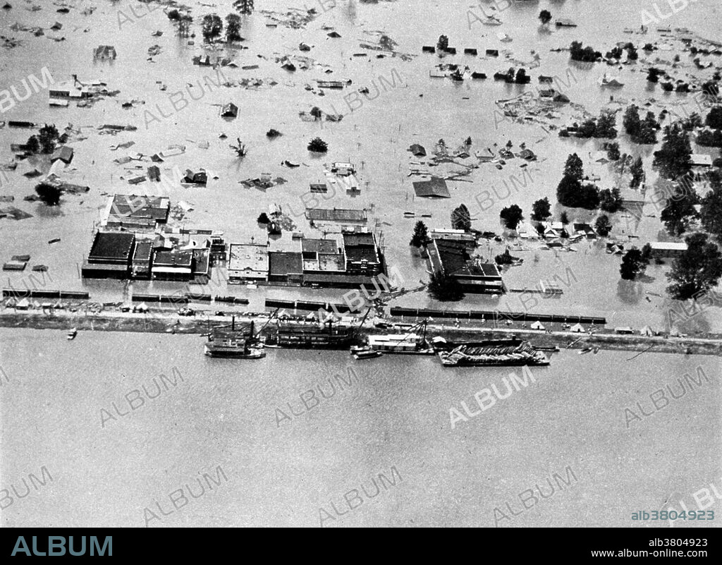The Great Mississippi Flood of 1927 was the most destructive river flood in the history of the United States. The flood began when heavy rains pounded the central basin of the Mississippi in the summer of 1926. By September, the Mississippi's tributaries in Kansas and Iowa were swollen to capacity. Flooding overtook the levees causing the Mounds Landing to break with more than double the water volume of Niagara Falls. The Mississippi River broke out of its levee system in 145 places and flooded 27,000 square miles. This water flooded an area 50 miles wide and more than 99 miles long. The flood caused over $400 million in damages and killed 246 people in seven states. The flood affected Arkansas, Illinois, Kentucky, Louisiana, Mississippi, Missouri, Tennessee, Texas, Oklahoma and Kansas. By May 1927, the Mississippi River below Memphis, Tennessee, reached a width of 60 miles. Photo originally captioned: "The Great Mississippi River Flood of 1927. Arkansas City, Arkansas on April 27, 1927. The river stage was at 52.8 feet." From: "The Floods of 1927 in the Mississippi Basin", Frankenfeld.