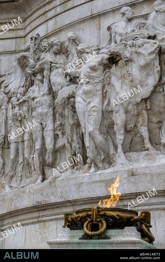 Rome, detail of the "Vittoriano" . The Altare della Patria (Altar of the Fatherland) also known as the Monumento Nazionale a Vittorio Emanuele II (National Monument to Victor Emmanuel II) or "Il Vittoriano" is a controversial monument built in honour of Victor Emmanuel, the first king of a unified Italy. It occupies a site between the Piazza Venezia and the Capitoline Hill.. The eclectic structure was designed by Giuseppe Sacconi in 1885; sculpture for it was parceled out to established sculptors all over Italy, such as Leonardo Bistolfi and Angelo Zanelli. It was inaugurated in 1911 and completed in 1925.. The monument is built of white marble from Botticino, Brescia, and features stairways, Corinthian columns, fountains, an equestrian sculpture of Victor Emmanuel and two statues of the goddess Victoria riding on quadrigas. The structure is 135 m (443 ft) wide and 70 m (230 ft) high. If the quadrigae and winged victories are included, the height is to 81 m (266 ft). The base of the structure houses the museum of Italian Unification.. In 2007, a panoramic elevator was added to the structure, allowing visitors to ride up to the roof for 360 degree views of Rome.