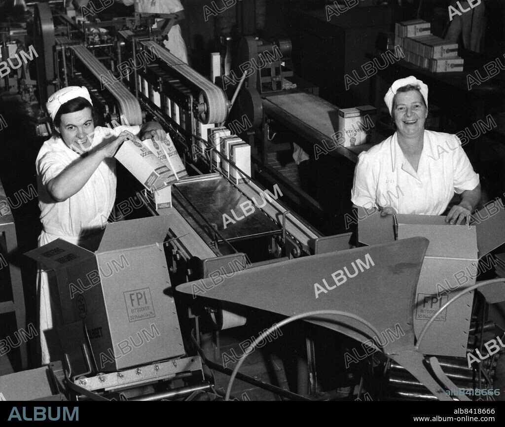 Arlöv 1953-01-15. Svenska Sockerfabriks AB (SSA, Sockerbolaget) i Arlöv 1953.. Damerna Elin Larsson och Dagny Ljunggren vid löpande bandet med sockerbitsförpackning. Foto Ture Hellström / Sydsvenskan / SCANPIX. **OUT Kvällsposten, Skånska Dagbladet, Metro Skåne**. ***BETALBILD***.
