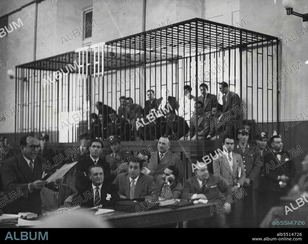 Gangsters Caged In Italy.Italian Gangsters are caged in a Naples police court October 31, as with their leader Giuseppe Lamarca (outside cage, Extreme Right, Dark suit) who is Managled, they face 51 charges of hold up, theft, blackmail and attacks on police. At left Dr. Luigi Caporale defence attorney for the men, reads a statement attorney for the men, reads a statement to the court. Lamarca has written his will, leaving a house to Caporale. This house, says the Bandit, will become a "holy Shrine" visited by thousands of pilgrims during Holy Year. November 3, 1949. (Photo by Associated Press Photo).