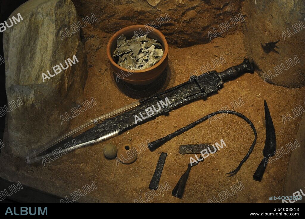 Celtic peoples. 3rd century BC. Recreation of a grave with stela. Burial pit possibly of a warrior chief for the objects of his funerary grave goods: an iron sword with damascene silver decoration, a banner auction, a razor and a tweezer. National Archaeological Museum. Madrid, Spain.