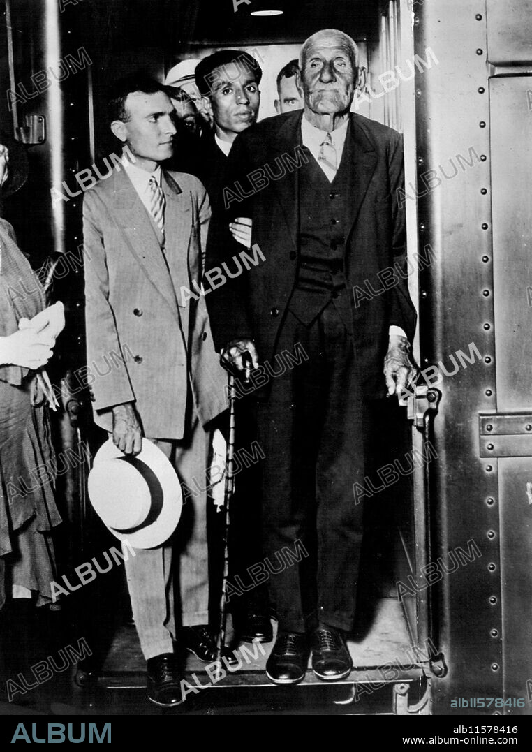 Zaro Agha, 156-year-old Turk, Arriving in New YorkZaro Agha, The oldest man in the world, being accompanied by his great-great-grandson, Ashuit Nussa 33, as he arrived in New York for the first time in the 156 years of his life. Nussa acts as interpreter for to his eleventh wife. He denies that he is seeking a mate in America. Through his interpreter he made it known to newspapermen that "The first hundred years are the Hardest." July 18, 1930. (Photo by International Newsphotos Inc.).