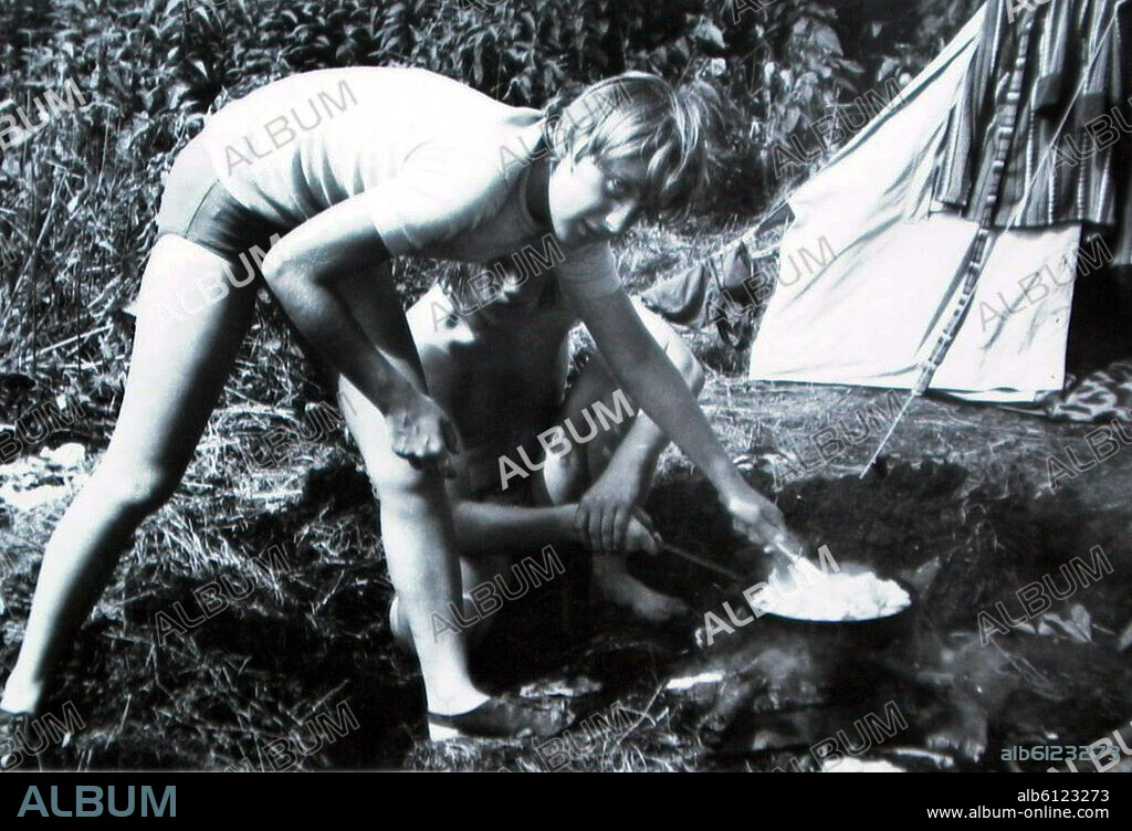 (dpa) - Angela Kasner, who has passed her school-leaving examination, prepares a meal on a fireplace while camping with friends in Himmelpfort, German Democratic Republic, July 1973. The person who was then a young girl is now called Angela Merkel and was elected Germany's first female chancellor on 22 November 2005. Photo: Bernd Gurlt.