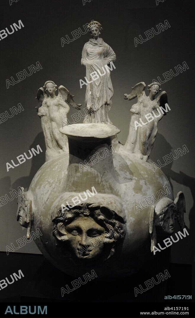 Ascos, 320-300 a.C. Sobre el asa y ambos lados del cuello de la vasija, tres figuras: una mujer, posiblemente la imagen de la difunta, es una terracota helenística. Las dos figurillas femeninas aladas y desnudas pueden corresponder a Eros o Afrodita, apoyadas en un pilar, con la mano en la cadera y una pierna cruzada por delante de la otra. En el frente y en los dos laterales del vaso tres gorgoneion, máscaras frontales de la Gorgona Medusa. Altura: 68,6 cm, anchura: 42 cm, profundidad: 48 cm. Procede de Canosa di Puglia, Italia. Museo Arqueológico Nacional. Madrid. España.
