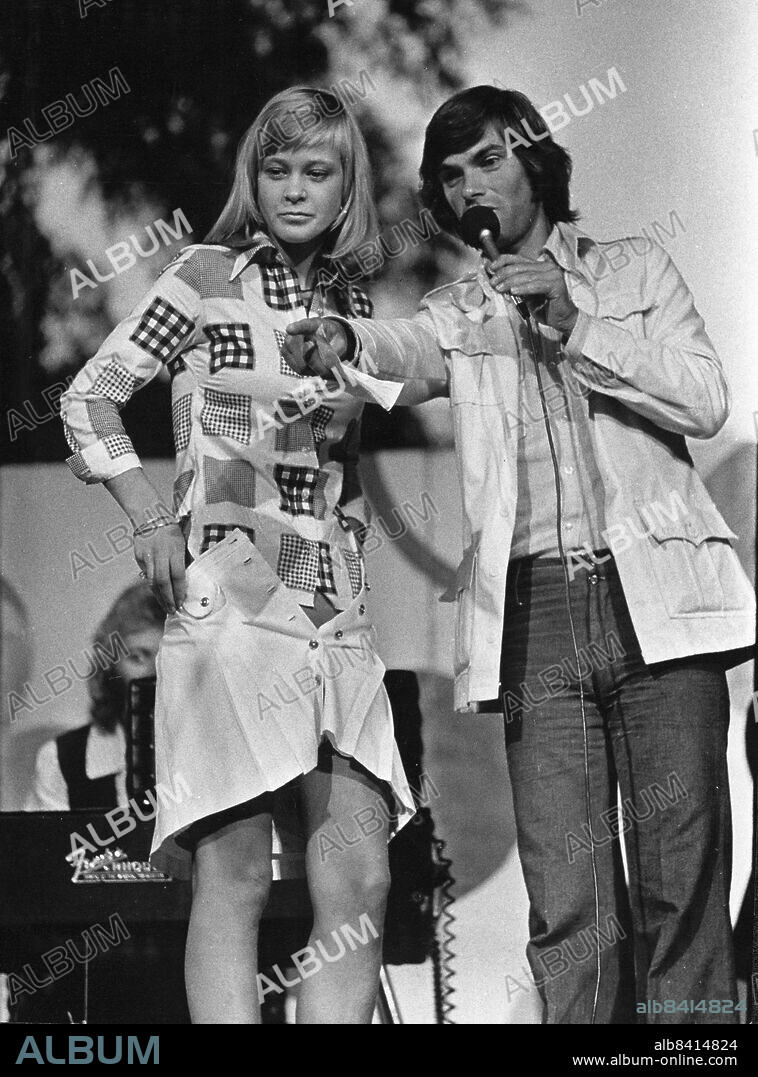 STOCKHOLM 1973-08-05. Underhållning i Kungsträdgården. Femtusen killar blir besvikna om de inte får se dej i bikini, sa konferencier Hans Wahlgren till Lena Carlsson. En söndagskväll i Sommar-Stockholm kan man få uppleva märkvärdiga saker. På Kungsträdgårdens scen står en 19-årig flicka från en bondgård mellan Flen och Katrineholm och klär av sej i bara bikini inför tio tusen åskådare. Sedan får hon visa publiken att hon varken kan sjunga eller dansa hambo. Hon får också hoppa rep äta ost och studsa på en känguruboll.. Foto: Per L-B Nilsson / DN / TT / kod 41. ** OUT SVD **.