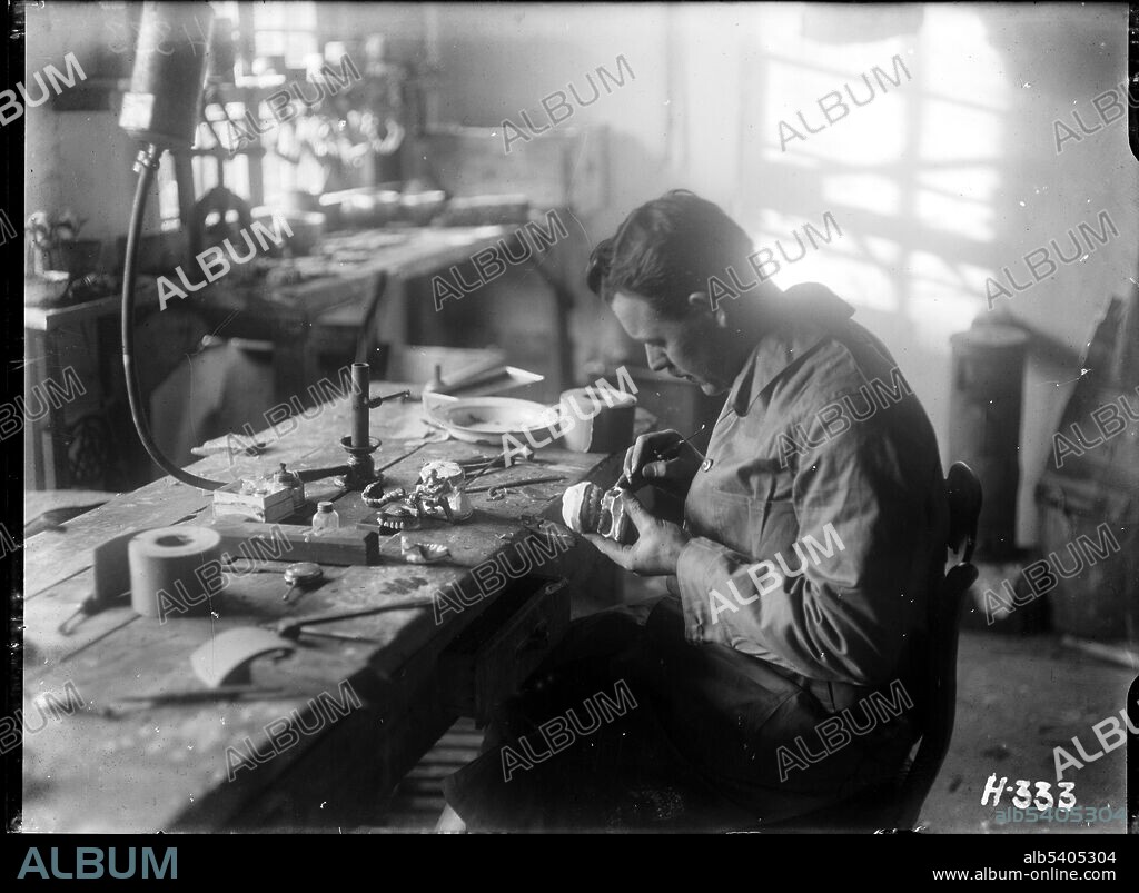 An army dental mechanic puts finishing touches to a new set of dentures manufactured at the New Zealand Dental Corps laboratory in Nielles, France. 1917 by Henry Armytage Sanders. Alexander Turnbull Library, Wellington.