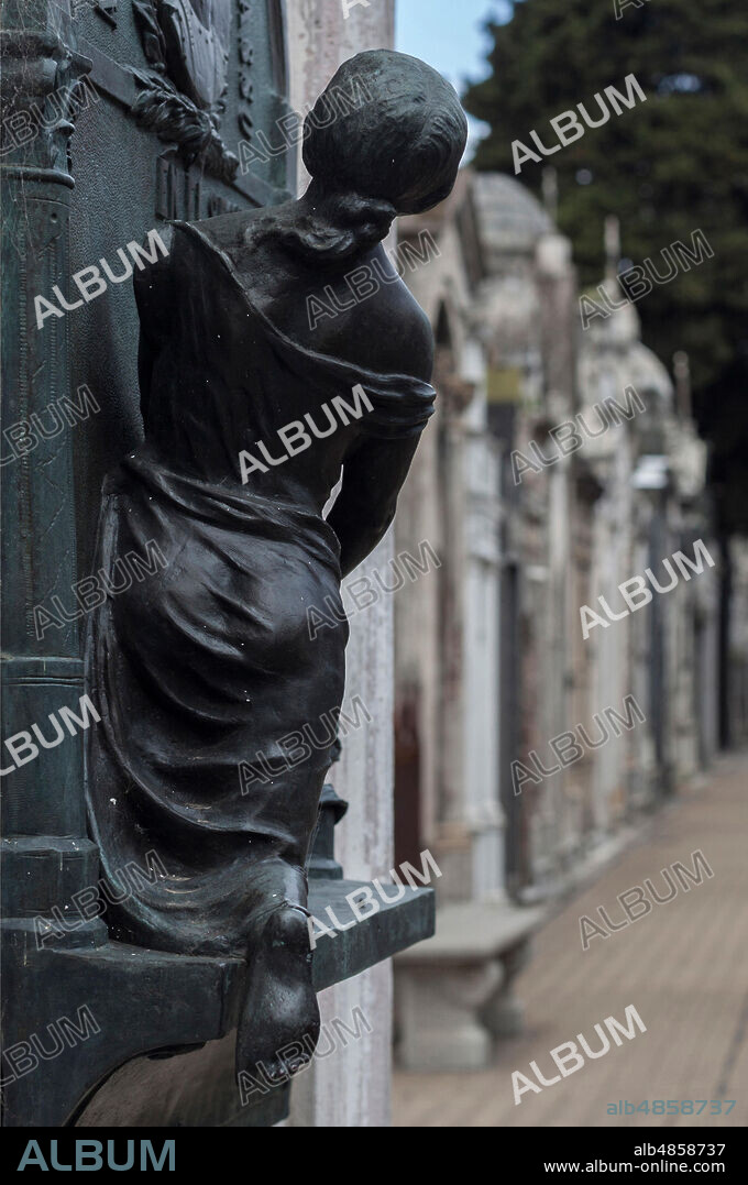 Escultura de joven mujer de espalda observando el pasillo del cementerio,.