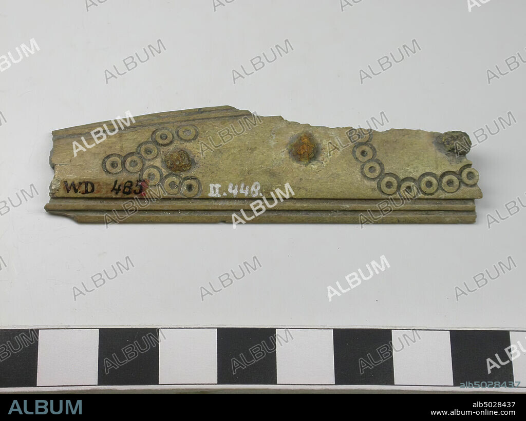 Fragment of a one-sided three-layer comb: part of a handle blade. Type: long comb. Decoration: handle leaf: dot circles forming a lying S and a lying V-shaped pattern. Lines that run parallel to the edges. Shape: straight base, slightly curved top. Tooth plates: 0. End plates: 0. Teeth: 0. Rivets: 3. Thin handle blade. Saw marks: So first the teeth plates and the handle blades have been attached to each other and then the teeth sawn in., Comb fragment, organic, antlers, l = 7,5 cm and b = 2,2 cm., Vmec 800-900.