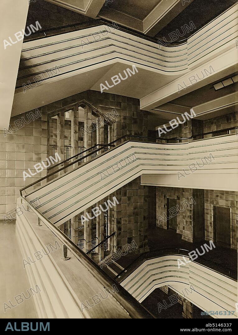 Photographenatelier Gebr. Dransfeld, Carl Dransfeld, staircase of the city hall, Wilhelmshaven, silver gelatine paper, black and white positive process, image size: height: 23.00 cm; width: 17.20 cm, stamp: FOTO-HAUS-DRANSFELD, OHLSDORFERSTR. 2, WINTERHUDER MARKET PLACE; Under each reproduction is to be printed, Foto Dransfeld, Lichtbildner, Hamburg 39, Ohlsdorferstr. 2 /Copyright, (Law of Jan. 9. 1907), Architectural Photography, City Hall, Stairs, Staircase, Interior Decoration (of a House), The Photo Studio Gebr. Dransfeld was founded in 1902 by the trained lithographer Carl Dransfeld and his brother, the painter Adolf Dransfeld, in Berlin and moved to Hamburg in 1904. Building director Fritz Schumacher commissioned the Dransfeld brothers to document the public buildings he had constructed since 1909. This prestigious commission established the Dransfeld brothers as leading architectural photographers in 1920s Hamburg. Among the architects for whom the studio worked were Fritz Höger, Martin Elsaesser, Distel & Grubitz or the Gerson brothers. With their photograph of the Chile House designed by Höger, Carl and Adolf Dransfeld created an icon of architectural photography. By creating a strong view from below and using a wide-angle lens, they reinforced the expressionist character of the building's top, thus contributing significantly to the popularity of modern Hamburg brick architecture. The Dransfeld brothers also captured the town hall in Wilhelmshaven, also built in 1928/1929 according to plans by Höger. (Sven Schumacher).