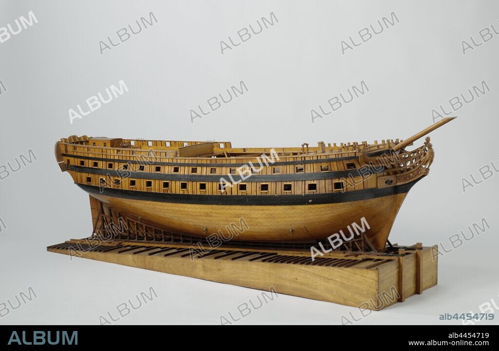 Model of a 74-Gun Ship on a Slipway, Construction model or the hull of a 74-piece line ship in the ropes on a slope, using the French launch method The skin is omitted on the port side under the barwood and on the starboard side above the barwood, on starboard a piece of skin with trusses can be removed in three places. Sixty-seven artillery ports spread over three decks, plus eight places for artillery firing. The galleon is only worked out on the port side: the figurehead is a woman in Roman robe with a laurel wreath in her hand. Twisted mirror with two gates in the wulf, the one-storey fence is adorned with allegorical figures, weapon trophies and an oval shield with wreath and branch, at the top two gates of the half deck. On the starboard side a one-storey side gallery with an open convenience above it. Straight rudder with square rudder king and holes for two rudder pins, six rudder sets and a care belt, double steering wheel on the half deck. Cow bridge deck and lower deck only indicated by their web, main deck, half deck and box deck are closed. Detached cabin on the half deck according to the French practice of the 'carrosse'. Walkways and deck beams over the pit: the starboard walkway is wide and is supported by wooden knees, the port side is narrow and has metal knees. The deck equipment consists of a double anchor bet, two double spindles, two single pumps and an impact pump, the ship's bell and a chimney for the galley on the deck, many loose grilles and shutters. Fifteen-part trusses and crossing cat tracks at the track of the big mast. All rest above the gates of the main deck, continuous rest and peace of mind. Fairly flat sheer, two barwoods and one deer. The underwater ship is a weak S-frame., France, anonymous, Amsterdam, c. 1797 - c. 1800, wood (plant material), brass (alloy), yarn, paint (coating), model: h 52.5 cm × w 148.2 cm × d 34.2 cm packaging capsule: h 51 cm × w 146 cm × d 39 cm.