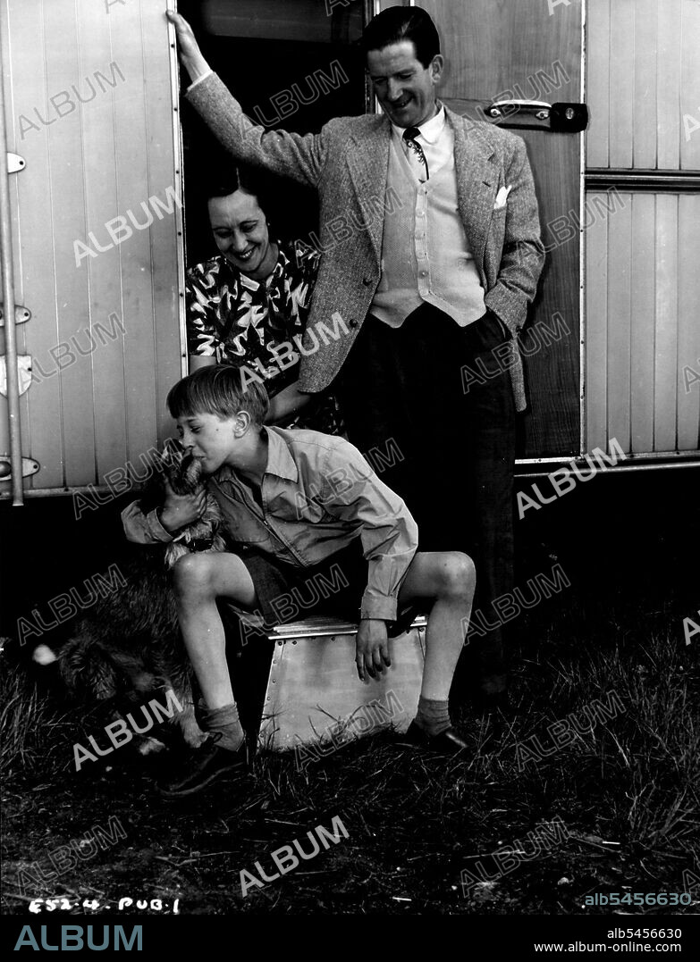 Thirteen-year-old Andrew Ray who stars with Kenneth More and Kathleen Ryan in the Associated British-Marble Arch Production 'The Yellow Balloon' with his mother and famous comedian father Ted Ray - hot forgetting Rusty - outside the family  caravan which was brought to Elstree Studios for the length of the production. In the caravan Mrs. Ray Cooked her son's meals and a tutor supervised his lessons. 'The Yellow Balloon' was produced by Victor Skutezky and directed by J. Lee Thompson. September 30, 1952.