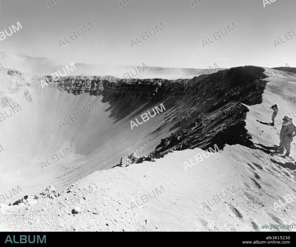 Storax Sedan, an underground 100-kiloton thermonuclear test conducted at Nevada Test Site on July 6, 1962 as part of Operation Plowshare, was a program designed to develop peaceful uses for nuclear explosives, such as canal and harbor building. Sedan left the largest man-made crater in the United States, displacing 12 million tons of earth and measuring 320 feet deep by 1280 feet in diameter. Here three men in protective suits stand at the edge of the crater.