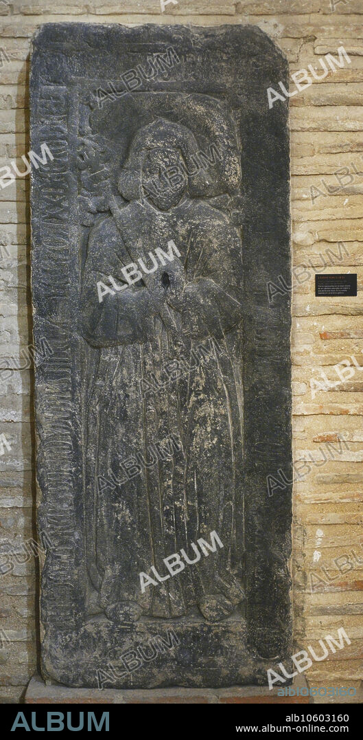 Lápida sepulcral. Bajorrelieve representando a un caballero vestido con hábito y portando una maza. En la cenefa inscripciones en caracteres góticos. Pizarra. Segunda mitad del siglo XIV. Procede de la Iglesia de San Román, Toledo. Museo de los Concilios y la Cultura Visigoda. Toledo. Castilla-La Mancha. España.