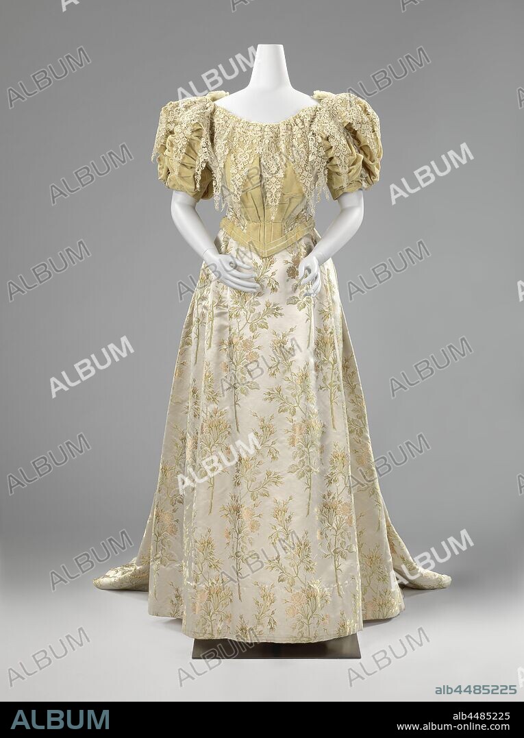 Evening Gown, Dress with a Vandyke Collar, Dress, consisting of a body (a) composed of gray beige launched silk with pink roses and yellow-green velvet and a skirt (b) with the same satin train. Matching bow (c) of yellow-green velvet. Model: (A) blushing body front and rear ending in a point with a low boat neck and puffy half-long sleeves. Lijf is composed of gaze de lisse, launched silk, velvet and velvet. The body is lined with pink taffeta and has ribs. Threaded closure at the back. Four square shoulder pieces of velvet on the puffing sleeves, lined with light green satin. The pointed lap is entirely of velvet. A large, neo-Renaissance style etching lace collar is attached over the body. Because of the complicated process, it was very expensive to find etching lace, invented in the course of the 19th century. (B) Running skirt with drag. Set on at the front, on the widened hips, three deep folds laid forward, two more deep folds behind. (C) Flat velvet bow., Van Kerm, Brussels, c. 1894 - c. 1895, geheel, zijde, lijf, voering, baleinen, cutting, l 148 cm × l 205 cm × w 65 cm l 107 cm l 170 cm l 43 cm × w 29 cm.