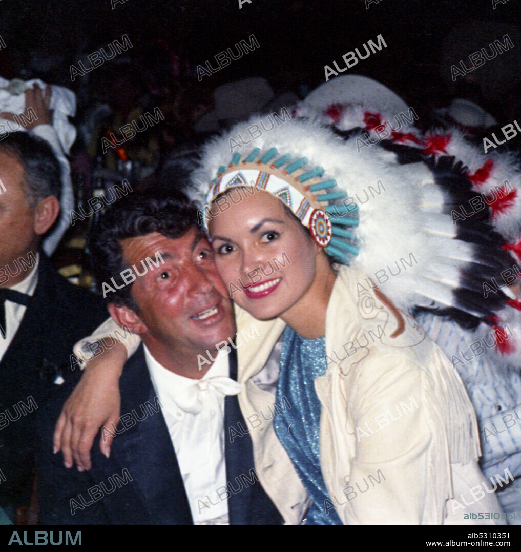DEAN MARTIN. Circa 1960, Los Angeles, California, USA: American actor DEAN MARTIN with Indian head-dressed beauty sitting on his lap.