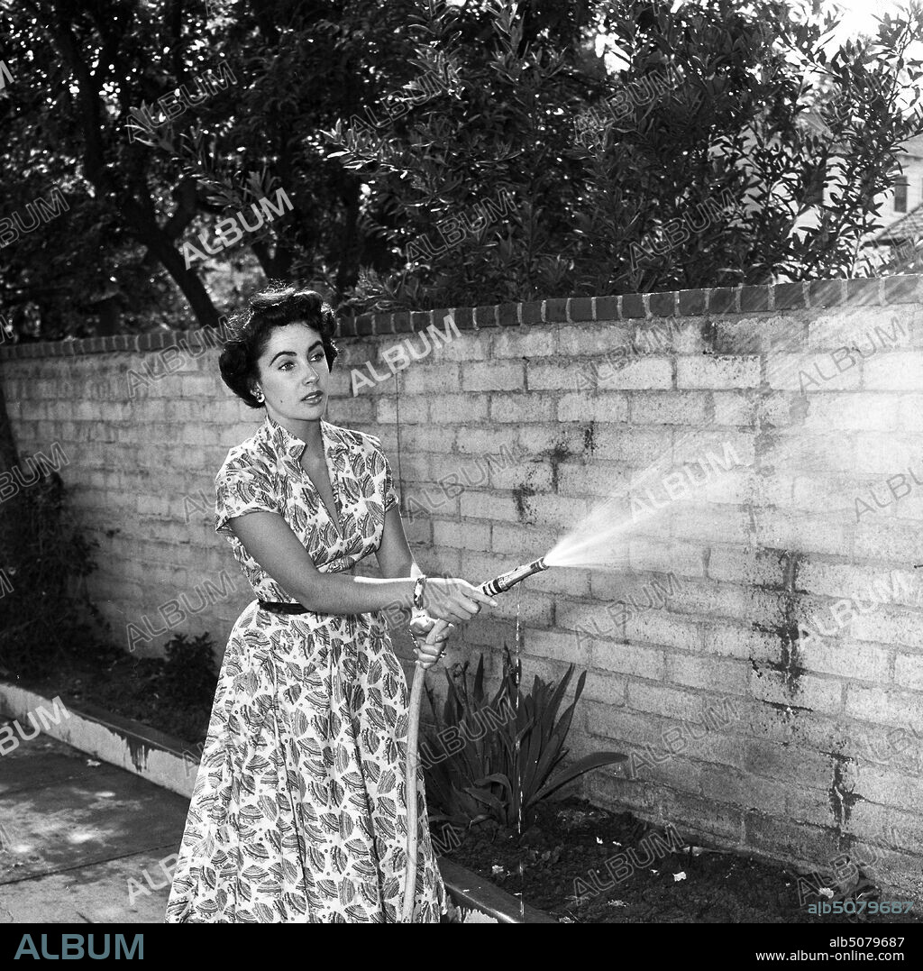 ELIZABETH TAYLOR. 1947, Los Angeles, California, USA: ELIZABETH (LIZ) TAYLOR in printed dress, watering plants with a garden hose in her backyard at home in Hollywood. (Credit Image: © Frank Worth/ZUMA Wire).
