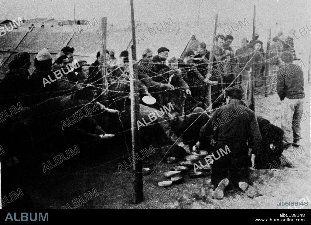 REFUGIADOS ESPAÑOLES DE LOS CAMPOS DE CONCENTRACIÓN DEL SUR DE FRANCIA RECIBIENDO ALIMENTOS A TRAVES DE LA ALAMBRADA DE LA POBLACION DE LOS ALREDEDORE.