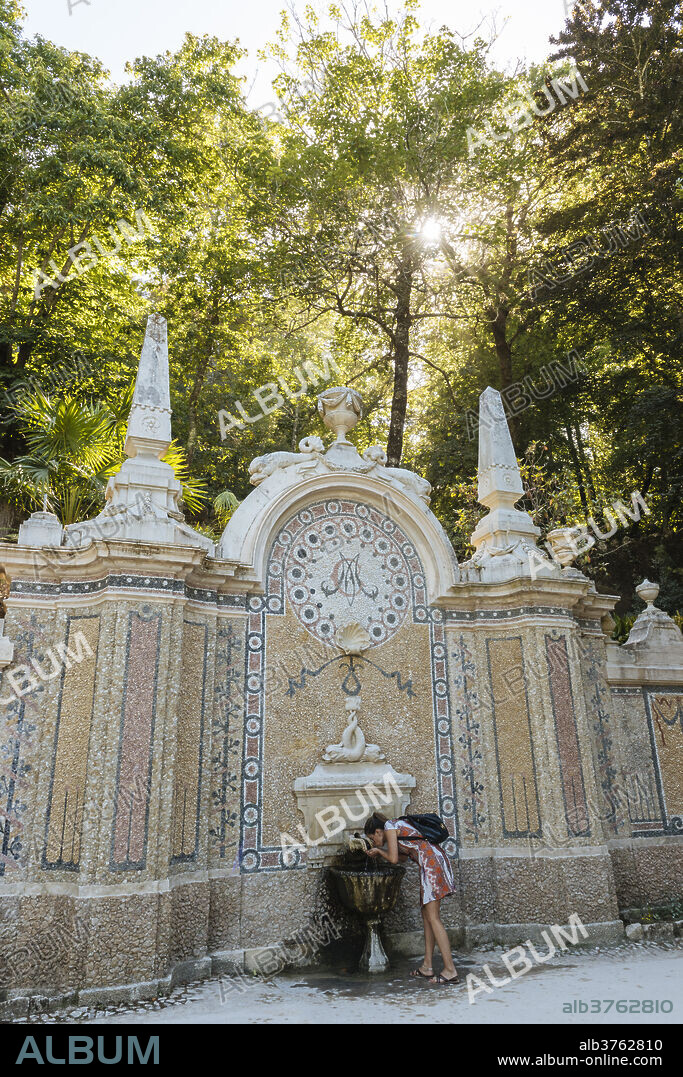 Woman using water fountain, Quinta da Regaleira, Sintra, Portugal, Europe.