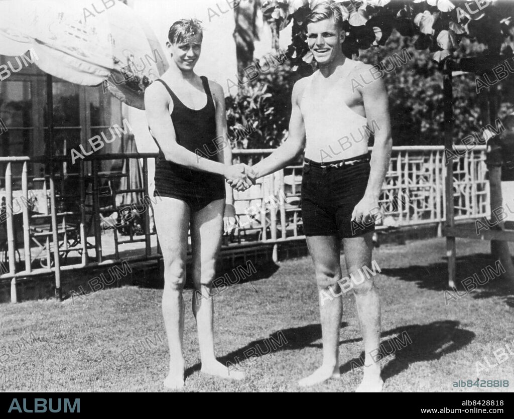 HAWAII HONOLULU 1924.. Orig. bildtext... 1/17 WORLD'S SWIMMING CHAMPION AND HAWAIIAN STAR TRAIN AT FAMOUS BEACH. WAIKIKI, T.H.- PHOTOS SHOWS: Arne Borg, of Sweden, World's champion swimmer and Buster Crabbe, Hawaiian star, who are competing in a series of meets on the famous Waikiki Beach. Not. (På Hawaii) Anm. A Borg, 1901-1987, en av Sveriges främsta simmare med bl a 32 världsrekord åren 1921-1929. C L Buster Crabbe, 1908-1983, amerikansk elitsimmare, skådespelare på 1930- och 1940-talet. Badkläder Handslag Konkurrenter Världsmästare CD589 persons: CLARENCE LINDEN BUSTER CRABBE;ARNE BORG sites: HONOLULU;SVERIGE*;HAWAII.