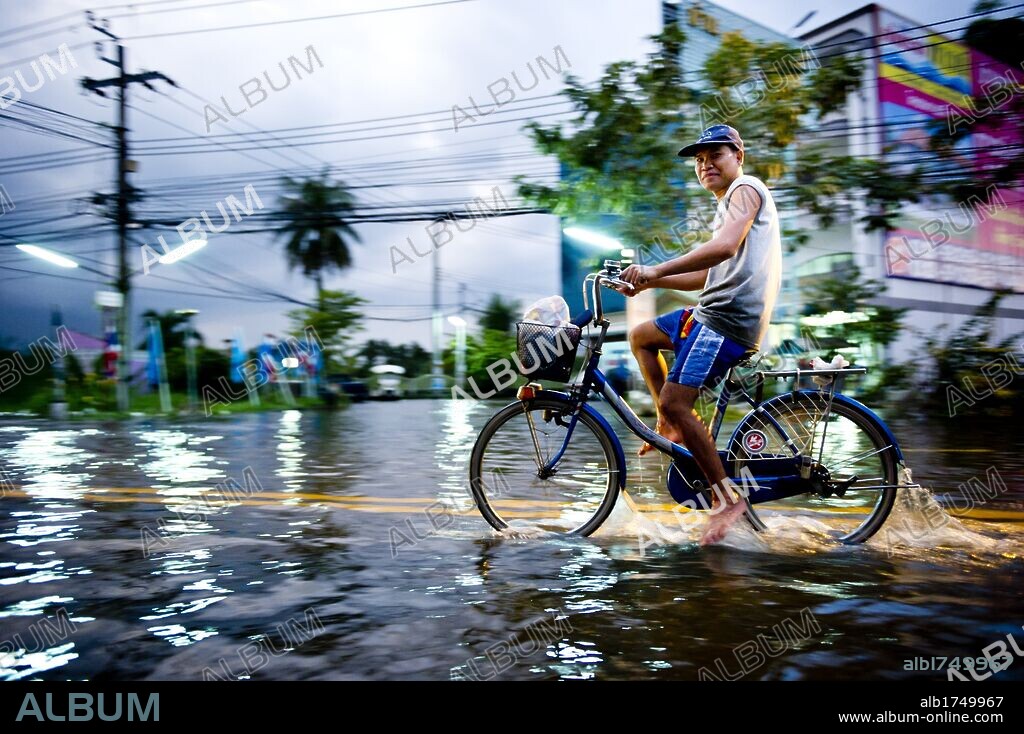 Oct. 25, 2011 - Nonthaburi, Thailand - A man rides his bicycle through floodwaters in Nonthaburi. Floodwaters breached barriers protecting Don Muang airport in Bangkok, forcing airlines to suspended their operations and diverting flights to Suvarnabhumi airport. (Credit Image: © Natthawat Wongrat/ZUMAPRESS.com). 25/10/2011