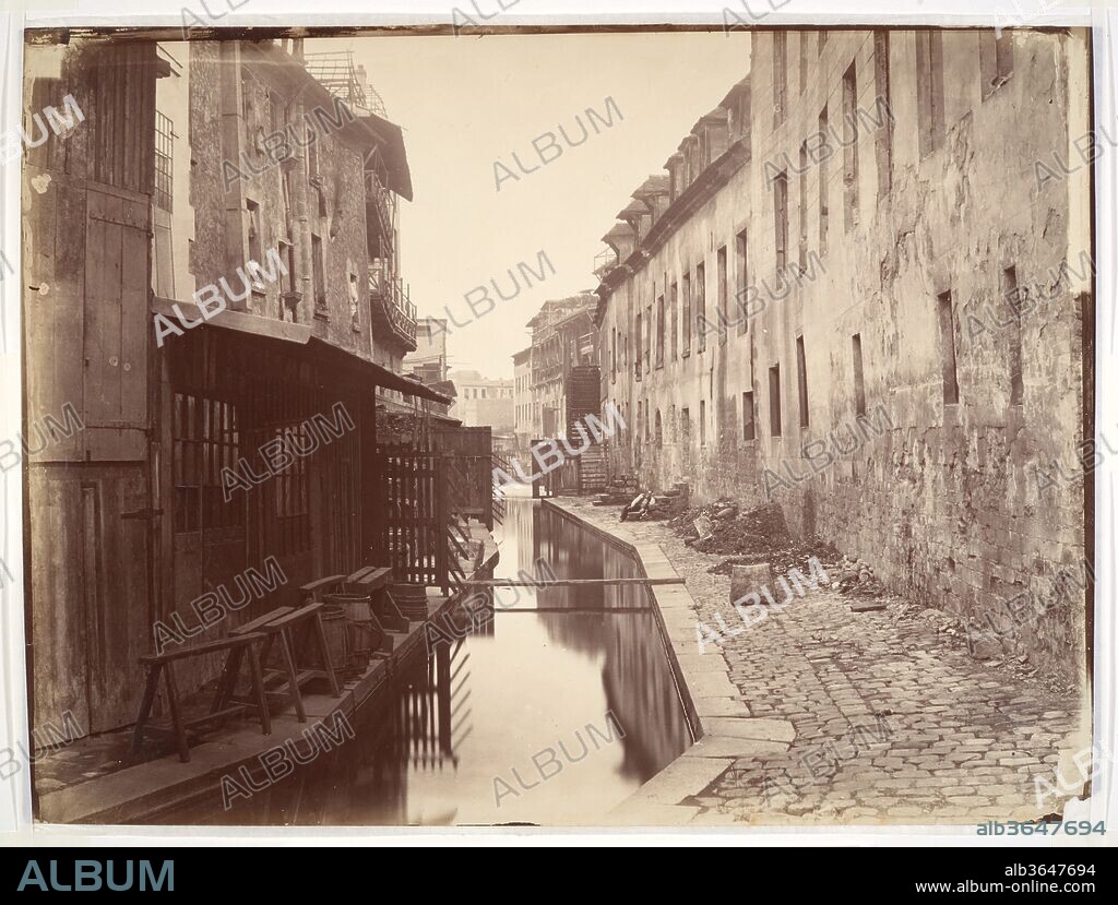 La Bièvre. Artist: Charles Marville (French, Paris 1813-1879 Paris). Dimensions: 27.8 x 37.6 cm. (10  15/16  x 14  13/16  in.). Date: ca. 1865.
As the official "photographer of the city of Paris," Charles Marville was charged with documenting the massive transformation of the city brought about by Napoleon III and his city planner, Baron Haussmann. In the early 1850s the Emperor proposed a network of grand boulevards that would plow through the narrow winding streets and overcrowded slums of Paris. Marville methodically recorded the streets and buildings slated for demolition, preserving an image for future generations. 
Although we may now look back at pictures like this one with nostalgia for a lost Paris, to Marville and his audience such scenes evoked a less bucolic reality-the Bièvre was essentially a waste system for twenty-four tanneries, twenty-one leather factories, nine starch and three dye manufacturers, a paper mill, two cotton and two flour mills, four laundries, a soap and candle factory, and assorted other industries. Shortly after Marville made this photograph, the Bièvre was simply covered over and tied into the Paris sewer system.
One motivation for Napoleon III's urban plan was to ease military movement and make it more difficult for revolutionaries to barricade narrow streets and control sections of Paris, but many of his efforts were genuinely geared toward transforming Paris into a safer, healthier, more modern city.