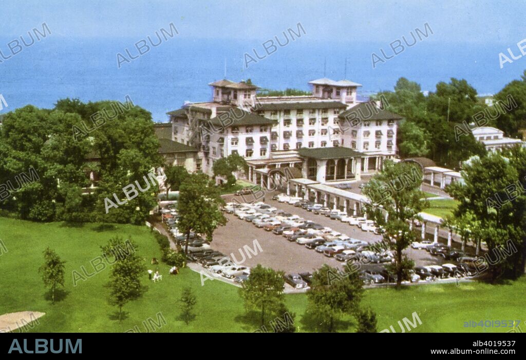 South Shore Country Club, Chicago, Illinois, USA, 1956. Postcard showing the exterior of the South Shore Country Club on Lake Michigan, the landscaped grounds and the parking lot. The building was designed by Chicago architectural firm Marshall and Fox in 1916. The club, founded in 1905, had tennis courts, a 9 hole golf course, a bowling green and a private beach on Lake Michigan. In the 1960s, as the neighbourhood became racially integrated, the wealthy white people who made up its membership began to move away. Refusing to admit black members (Jews had also been banned from joining since the 1930s), the club declined and closed in 1973. Today the building houses the South Shore Cultural Center.