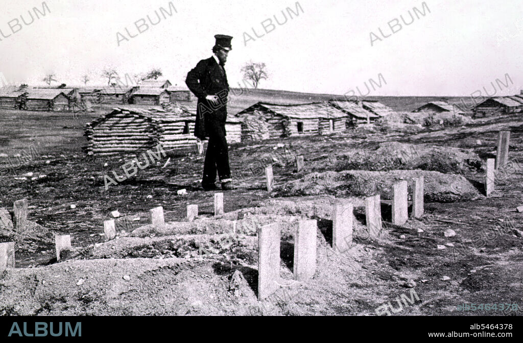 A bearded man wearing a frock coat and tall hat (intended to represent President Abraham Lincoln?) stands at the graves of soldiers who died during the Battle of Bull Run. circa 1862.