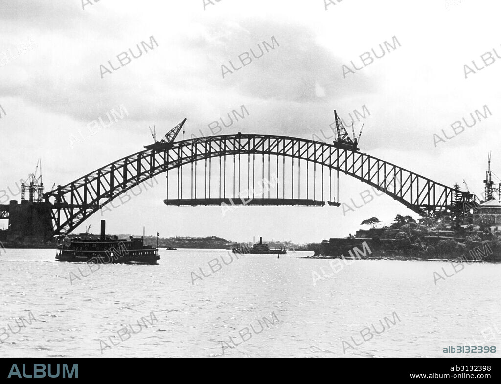 Sydney, Australia:  c. 1930 A vehicle ferry passes by the Sydney Harbour Bridge under construction between the Sydney business district and the North Shore.
