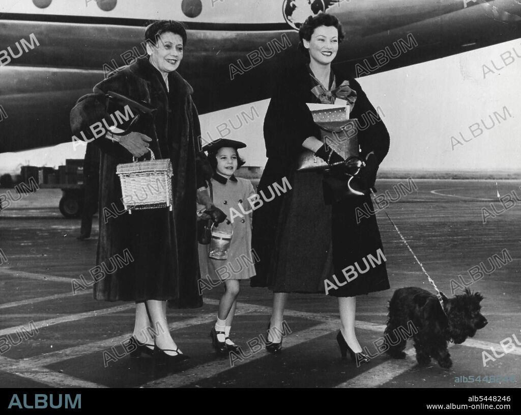 Ali Has Proposed -- Gene Tierney with her mother and her daughter Nina Cassini, when they arrived in New York for, Christmas. When film star Gene Tierney arrived in New York recently to spend Christmas with her family, she told reporters that "Ali Khan" proposed to me 8 months ago, but I did not make up my mind. He is always and the move. Much too busy with horses and racing cars. I am the home type. I like to be with the family in front of the fire." December 29, 1953. (Photo by Paul Popper).