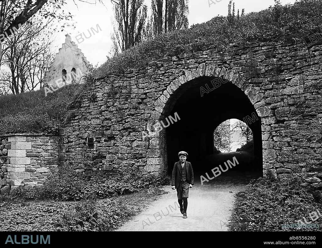 ARKIV 1931 . Pojke med keps på gångstigen under muren till södra slottslängan som är det som finns kvar av slottet Visingsborg på Visingsö. Visingsborg började byggas på 1570-talet men avslutades först 1660 och var centrum för släkten Brahes grevskap. När grevskapet drogs in till kronan 1680 övergavs slottet som senare användes som fångläger.. Remains of the castle Visingsborg from 1570.. Foto: TT / Kod 1900.