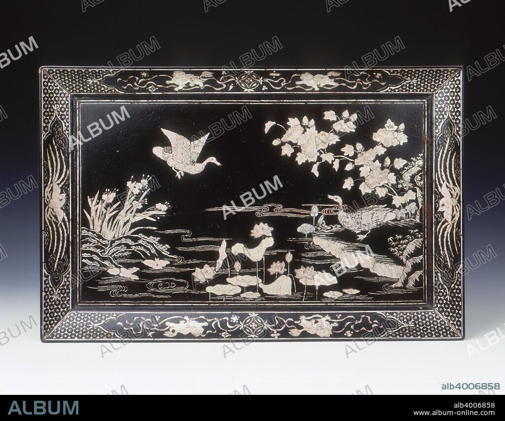 Black lacquer tray with mother-of-pearl inlay of ducks by lotus pond, Ming dynasty, China, 2nd half of 16th century. A rectangular black lacquer tray decorated with mother-of-pearl inlays of two ducks; one in flight and the other by a lotus pond under a peony tree with narcissi on the opposite bank. The sloping sides are decorated with Buddhist lions with brocaded balls and precious emblems on the long sides in panels on the longer sides and two phoenixes in flight in panels on the shorter sides.