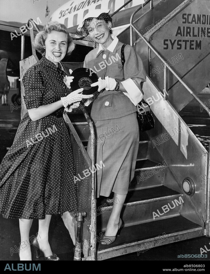 USA NEW YORK 1952-06.. Orig. bildtext... BIBI JOHNS, NEWEST SWEDISH NIGHTINGALE, gives her first American recording The Night is Filled With Echos, to beautiful Signe Hasso, to deliver to friends in her native Sweden, as the later departed today from New York international Airport via Scandinavian Airlines. Miss Hasso, en route to Rome, will film a new series of TV films. Anm. Sångare Skådespelare Flor Handskar Prickigt CD279 persons: SIGNE HASSO;BIBI JOHNS sites: SVERIGE*;NEW YORK;USA.