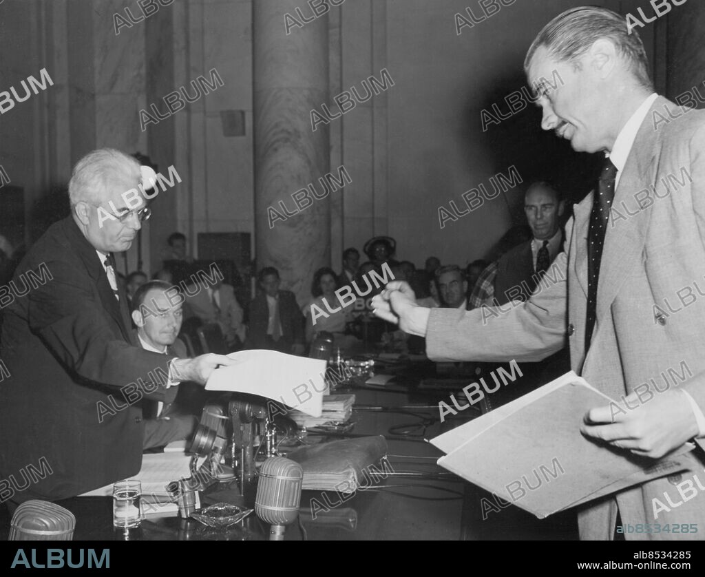 Orig. bildtext... PLANE BUILDER PREPARES QUESTIONS FOR SENATOR Washinton, D.C. Howard Hughes, millionaire plane builder, resuming the stand before the senate war contract investigation committee today, branded the denial made by senater Owen Brewster of Maine, to Hughes' blackmail charges a pack of lies, and presented to senator Homer Ferguson of Michigan, subcommittee chairman who presides at the probe, two typewritten pages of questions which he asked the committee to put to senator Brewster. Hughes is on the right here. Anm. H Hughes, 1905-1976, amerikansk industriman, flygare och filmproducent Förhör angående affärer under kriget Papper CD358 persons: HOWARD HUGHES sites: WASHINTON D C;USA.