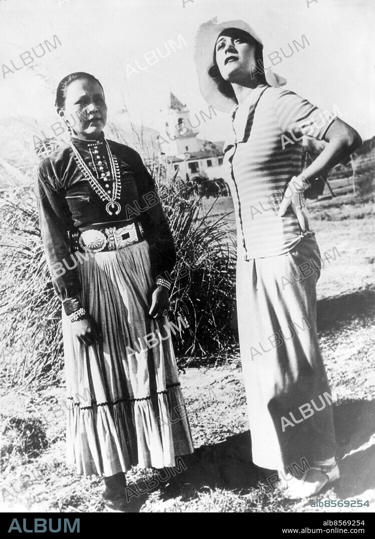 Orig. bildtext... POLA NEGRI MEETS INDIA PRINCESS. Photo shows:- Pola Negri the famous film actress, chatting with Na Glee Monaba (The Peacemaker), Princess of the Navajo trive of Indians living in the section at Palm Springs, California, during her visit to California to recuperate from her long illness. US Jan 30th 1932 Anm. P Negri, 1894-1987, polsk-amerikansk skådespelerska. Traditionell klädsel Randigt Ränder Kjolar Skärp Halsband Halssmycken Handen i sidan Handskar Läppstift Indianstammar Filmstjärnor Prinsessor CD580 persons: NA GLEE MONABA;POLA NEGRI sites: POLEN*;USA;PALM SPRINGS.