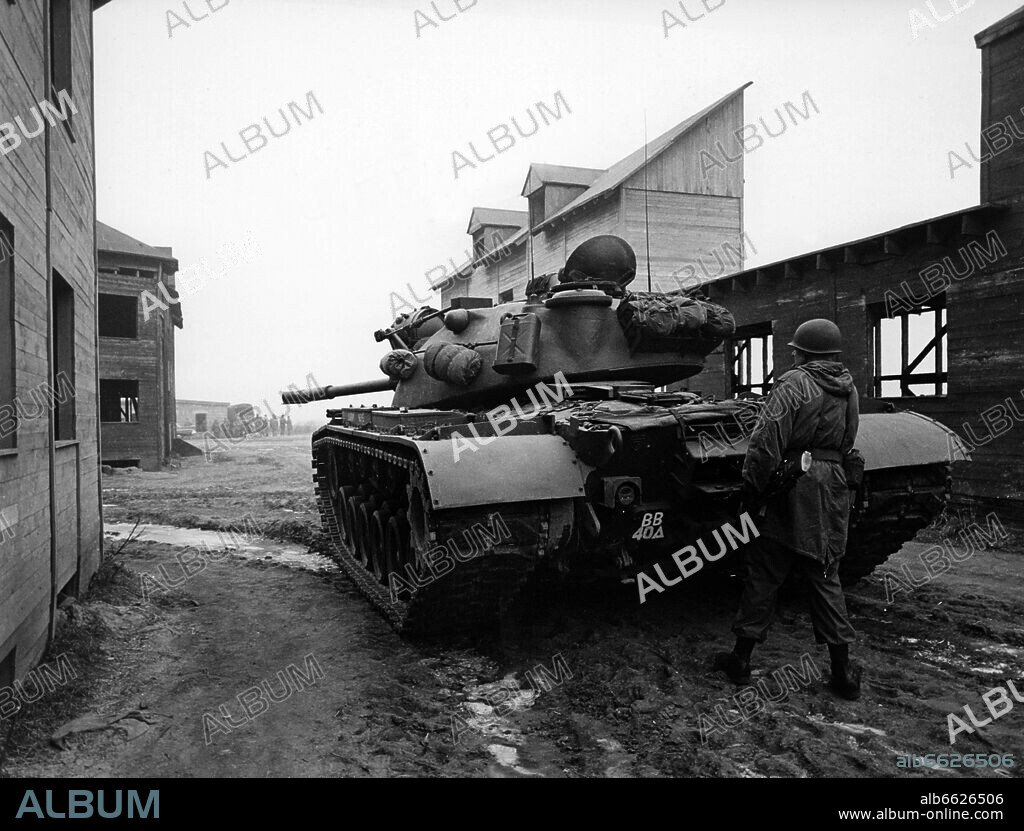 A soldier of the US army takes cover behind a tank during an exercise on the 27th of December in 1961 in the ghost village "Parks Range" in Berlin-Lichterfelde, which was especially built for army training. 27/12/1961